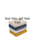 Stack of folded towels in beige, blue, white, and yellow with promotional text 'buy two, get two free' on a white background.