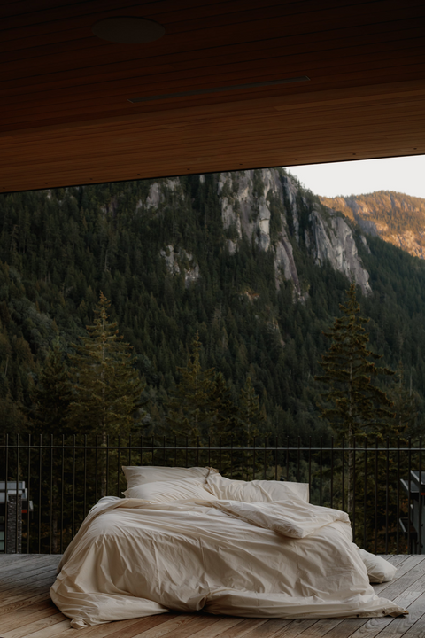 Takasa organic bed sheets in natural, outdoors overlooking a mountain and trees
