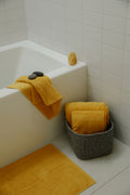 Organic bath towels in mustard yellow on a bath tub- by Takasa.co