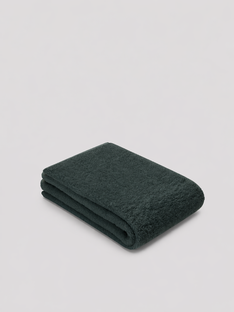 Folded Grove green towel on a light gray background